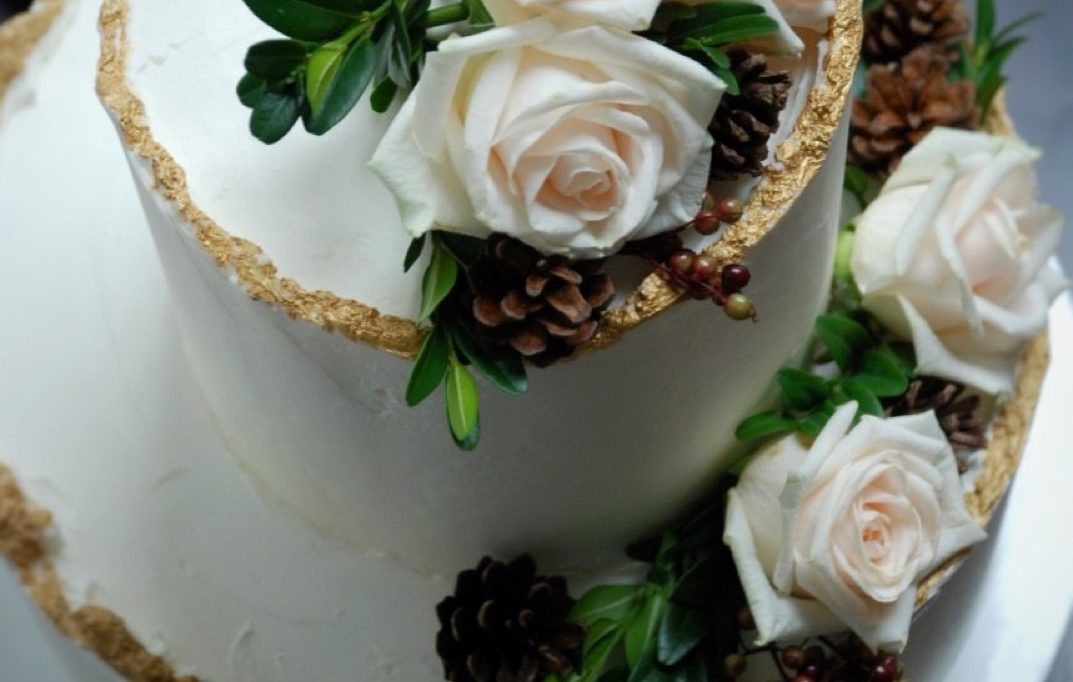 Wedding cake winter theme with wavy gold edges, roses and pine cones